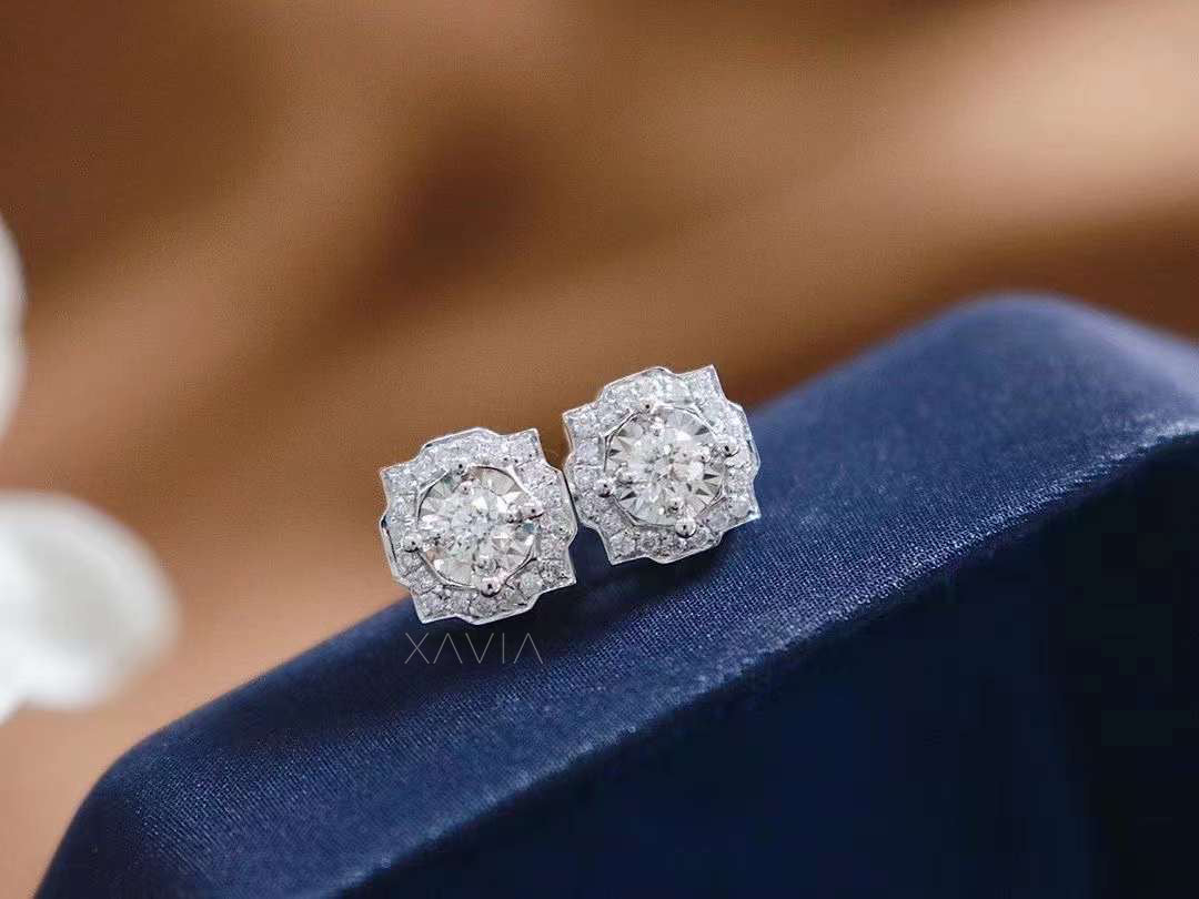 Close-up of round illusion halo diamond studs on navy velvet fabric